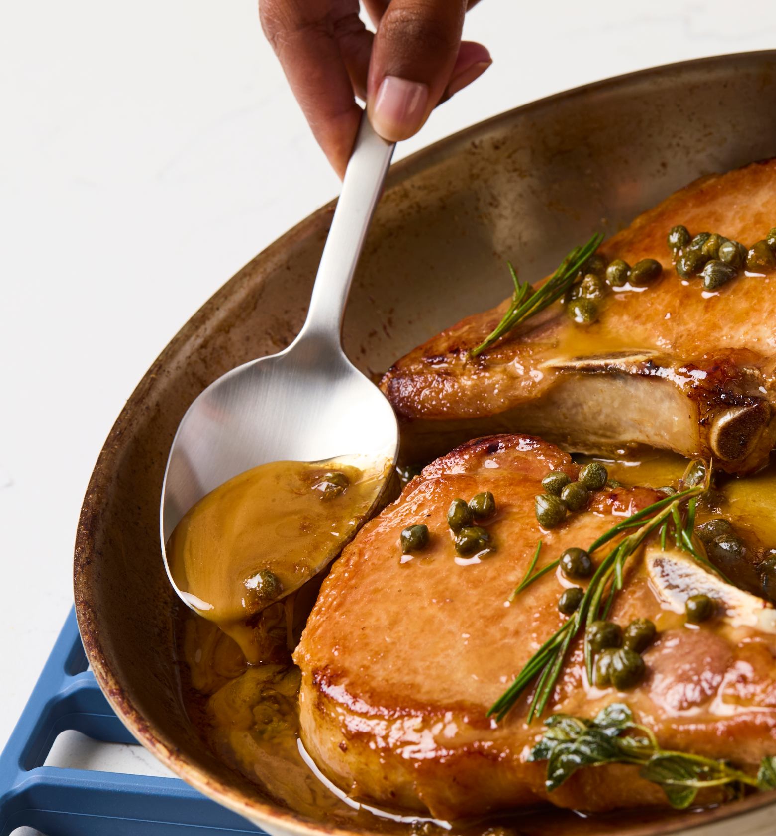Pan-seared pork chops with capers, rosemary, and golden pan sauce in skillet